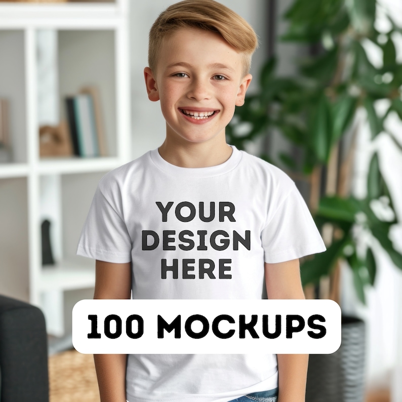 Pu&ograve; includere: Un giovane indossa una maglietta bianca con la scritta nera "YOUR DESIGN HERE". Sotto, un rettangolo bianco con le parole "100 MOCKUPS" in nero. La persona sorride.