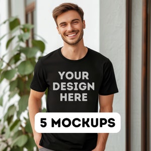 以下が含まれることがあります： 「YOUR DESIGN HERE」という文字が前面に印刷された黒いTシャツのモックアップ。5 MOCKUPS.