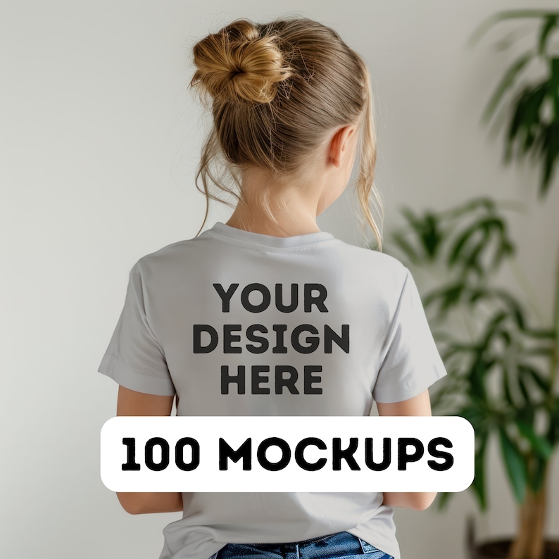Pu&ograve; includere: Una maglietta grigio chiaro con la scritta "YOUR DESIGN HERE" stampata sul retro in lettere nere. Sotto, un rettangolo bianco con le parole "100 MOCKUPS" in nero. La persona &egrave; di spalle.