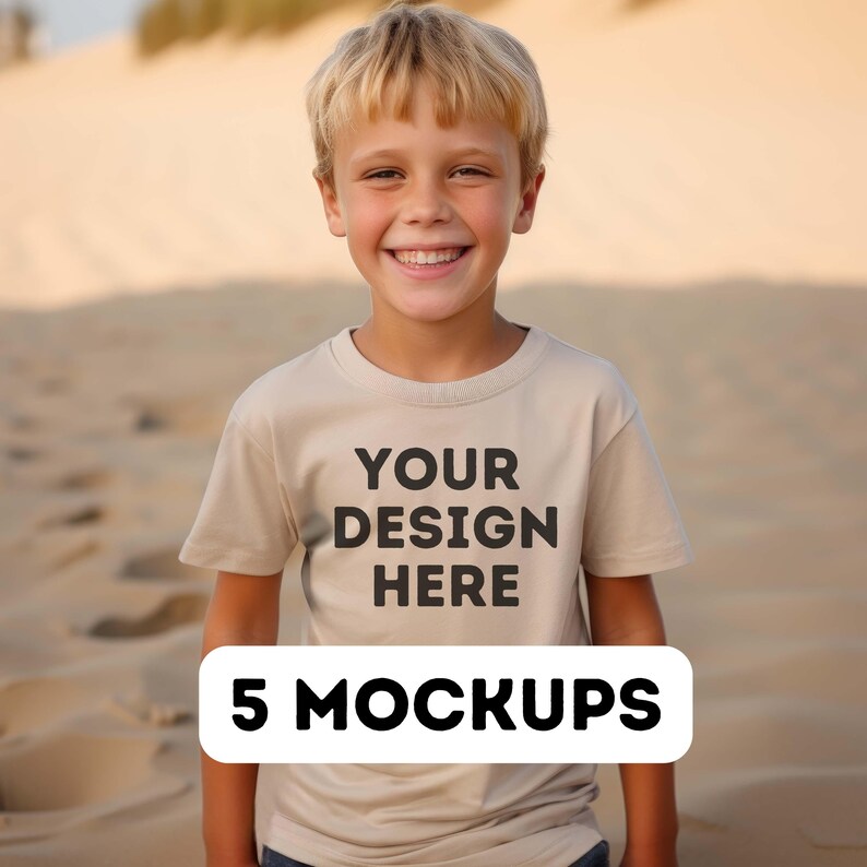 May include: A young person wearing a beige t-shirt with the text "YOUR DESIGN HERE" printed on the front. The t-shirt is a mockup for a design project. The person is standing in front of a sandy background. 5 MOCKUPS is written in a white rectangle at the bottom of the image.