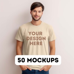 May include: A beige t-shirt mockup with the text "YOUR DESIGN HERE" printed on the front. The t-shirt is being worn by a person with short brown hair. The text "50 MOCKUPS" is printed in black on a white oval shape.