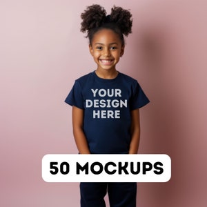 May include: A young person wearing a navy blue t-shirt with the text "YOUR DESIGN HERE" in white. A white banner at the bottom of the image reads "50 MOCKUPS". The background is a solid pink color.