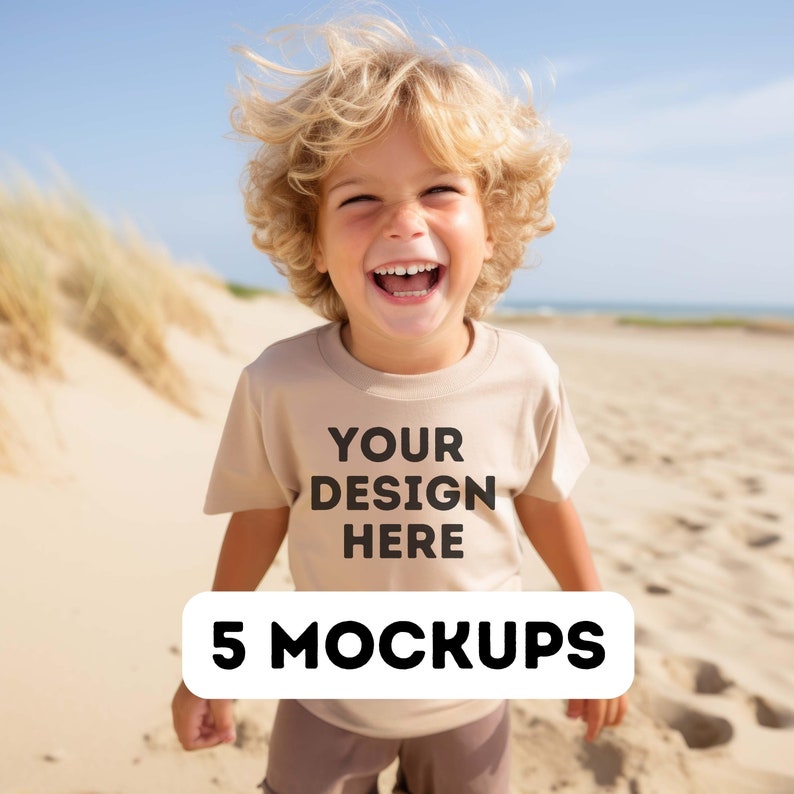 May include: A young child wearing a beige t-shirt with the text "YOUR DESIGN HERE" printed on the front. The child is smiling and standing on a sandy beach. 5 MOCKUPS.
