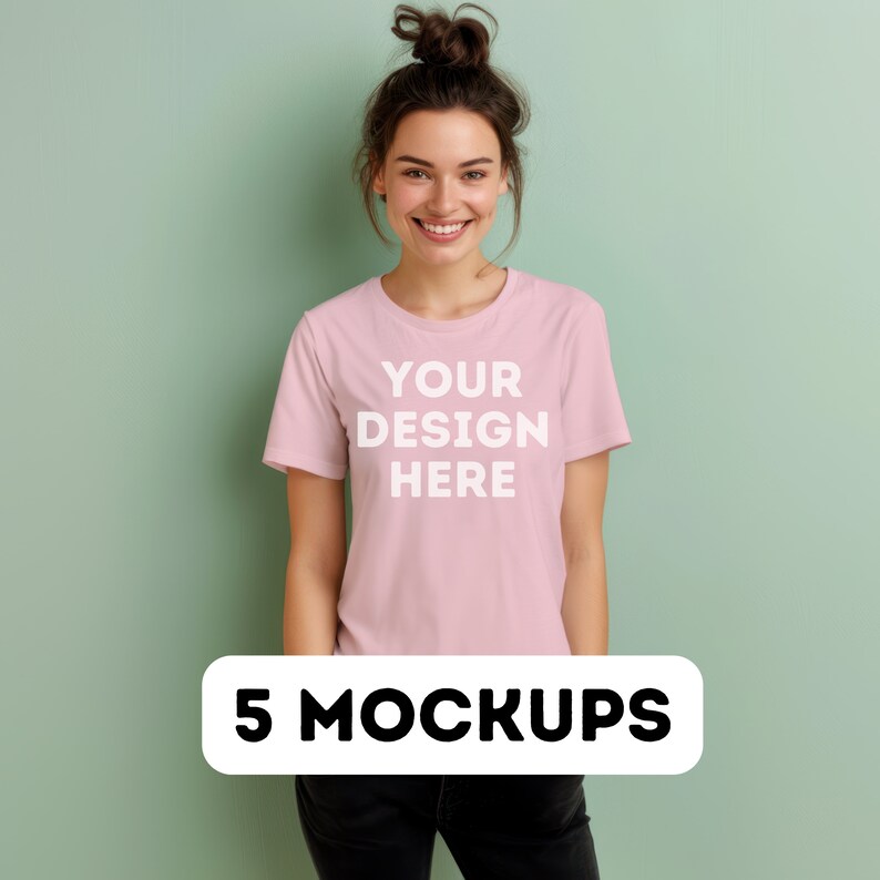 May include: A pink t-shirt with the text "YOUR DESIGN HERE" printed on the front. The t-shirt is being worn by a person with a light green background.