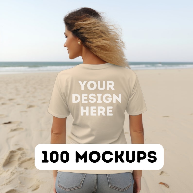 May include: A woman wearing a beige t-shirt with the text "YOUR DESIGN HERE" on the back. She is standing on a sandy beach with the ocean in the background.