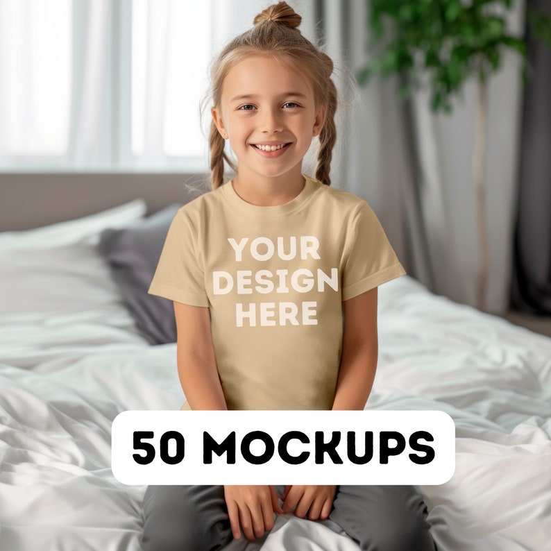 May include: A young person wearing a tan t-shirt with the text "YOUR DESIGN HERE" in white. The words "50 MOCKUPS" are displayed in a white rectangle at the bottom of the image. The person is sitting on a bed with white sheets.