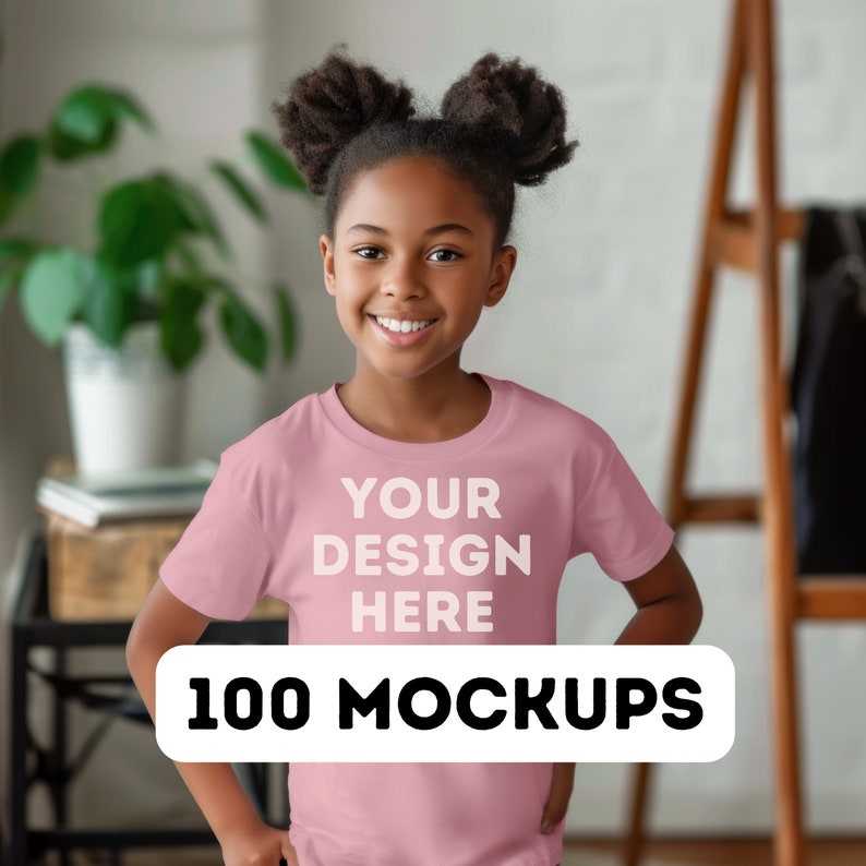 Pu&ograve; includere: Una persona indossa una maglietta rosa chiaro con la scritta bianca "YOUR DESIGN HERE" e "100 MOCKUPS". La persona sorride. Lo sfondo include una pianta e una struttura in legno.