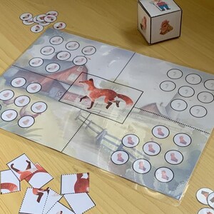 Könnte beinhalten: Ein Spielbrett mit einem roten Stall, einem Fuchs und einem Würfel. Das Brett ist in vier Abschnitte unterteilt, die jeweils eine unterschiedliche Anzahl von Kreisen haben. Es gibt auch mehrere kleine Kreise, die über das Brett verteilt sind.