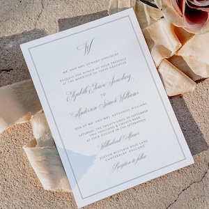 Puede incluir: Una invitación de boda formal con un borde gris y una escritura elegante. La invitación incluye los nombres Elizabeth Louise Jonesbury y Anderson Simon Williams, junto con la fecha y hora de la ceremonia. Una rosa y una cinta están en el fondo.