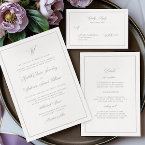 以下が含まれることがあります： エレガントなウェディング招待状セット、花の配置付き。 セットには、メインの招待状、返信カード、詳細カードが含まれており、すべてクラシックなデザインとグレーのボーダーが付いています。 招待状のテキストは優雅なスクリプトフォントです。
