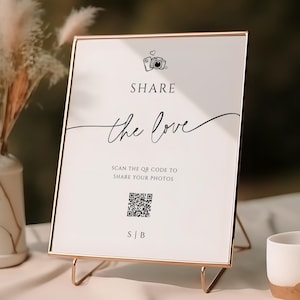 May include: A rose gold metal framed sign with the words "SHARE the love" in black script. The sign includes a QR code and the text "SCAN THE QR CODE TO SHARE YOUR PHOTOS". A white ceramic cup with a rose gold base is in the foreground.