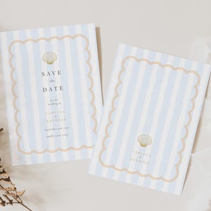 May include: Two Save the Date cards with a light blue and white striped background. The cards have a scalloped gold border and a gold seashell graphic. Text on the card reads "Save the Date" and wedding details.