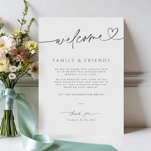 Può includere: Un cartello di benvenuto per matrimoni con la parola "welcome" in elegante calligrafia, un bouquet di fiori e un nastro verde menta. Il cartello recita "Family & Friends" e include un messaggio di ringraziamento firmato da Sarah & Blake.