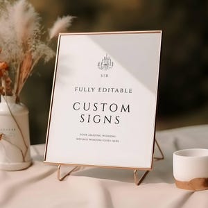 Könnte beinhalten: Ein goldfarbener Schild mit dem Text "FULLY EDITABLE CUSTOM SIGNS" und "YOUR AMAZING WEDDING MESSAGE WORDING GOES HERE". Das Schild steht auf einem goldenen Ständer und hat oben in der Ecke eine kleine Lüstergrafik.
