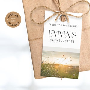 May include: White thank you tag with the text "Thank you for coming Emma's Bachelorette" and a photo of a field of tall grass with the sun shining through.