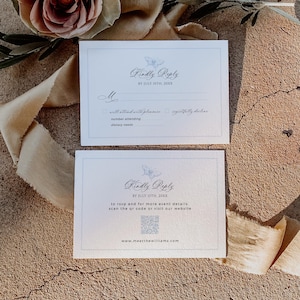 May include: Two white RSVP cards with a butterfly design and the text "Kindly Reply". The cards include fields for the guest's name, attendance, and dietary requirements. The bottom card has a QR code and website address.