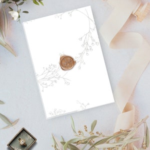 May include: A white card with a delicate floral design in grey and a wax seal with a floral pattern in brown.