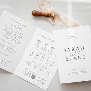 Peut inclure: Ensemble de faire-part de mariage blanc avec texte noir, comprenant un programme à trois volets et une carte de bienvenue. Les noms "Sarah et Blake" sont mis en évidence. Un tampon en bois avec un sceau doré est posé dessus.