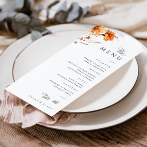 May include: A white wedding menu card with a floral design in shades of orange and brown. The menu includes a starter, mains, sides, and dessert. The text on the card reads "The Menu" and "Let's eat Sarah & Blake".