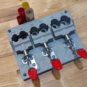 May include: A gray 3D printed tool with three clamps and labeled slots for different sizes of round objects. The slots are labeled 1/10, 2/10, 2/0, 1/6, 1/2, and 1/0. The clamps have red handles.