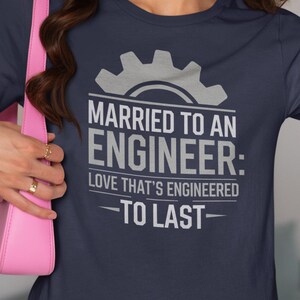 Può includere: Maglietta blu navy con una grafica di ingranaggio bianca e il testo "Sposato con un ingegnere: Amore progettato per durare".