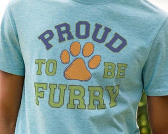 May include: A light blue t-shirt with a paw print graphic and the text "PROUD TO BE FURRY" in a collegiate font.