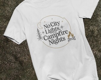 Könnte beinhalten: Weißes T-Shirt mit einem braunen Kreis-Motiv, auf dem "No City Lights, Just Campfire Nights" steht. Das Motiv enthält außerdem einen Mond, Sterne, eine Kiefer und ein Lagerfeuer.