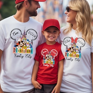 Puede incluir: Tres personas con camisetas blancas y rojas a juego con un dise&ntilde;o de Disneyland. Las camisetas presentan un contorno de la cabeza de Mickey Mouse con el texto "Disneyland Family Trip" y el a&ntilde;o 2026. Las camisetas son un recuerdo de viaje familiar.