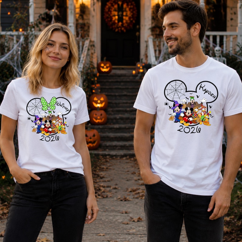 May include: Two white short-sleeve t-shirts featuring a graphic of Mickey Mouse and friends in Halloween costumes inside a Mickey-shaped outline. The design includes a spiderweb, the year 2026, and the personalized names Whitney and Kayden.