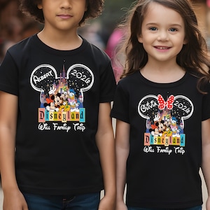 Puede incluir: Camisetas negras con un dise&ntilde;o en forma de Mickey Mouse. Las camisetas muestran el texto "Albert 2020 Disneyland Will Family Trip" y "Olivia 2020 Disneyland Will Family Trip" con gr&aacute;ficos coloridos de personajes de Disney.