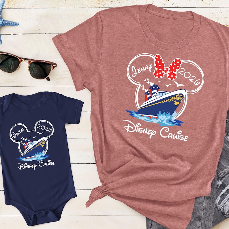 May include: A dusty rose t-shirt and a navy blue onesie featuring a Disney Cruise design. The design includes a cruise ship, Minnie Mouse ears, and the text "Jenny 2026" on the shirt and "Walter 2026" on the onesie.