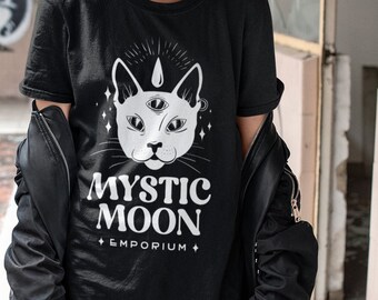 May include: A black t-shirt with a white graphic of a cat with three eyes and the text "Mystic Moon Emporium".