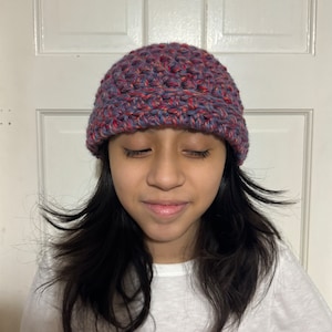 May include: A purple and red crocheted beanie hat with a slouchy fit.