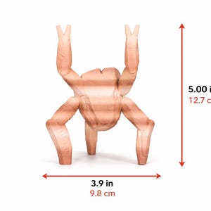 May include: A light brown, abstract wooden sculpture resembling a chicken. The sculpture is 5.00 inches (12.7 cm) tall and 3.9 inches (9.8 cm) wide. It has two arms raised and two legs extended.