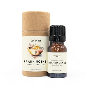 May include: A brown glass bottle with a black cap containing Frankincense essential oil. The bottle is labeled with the brand name "avivni" and the text "100% Pure & Organic Frankincense Essential Oil 0.33 fl oz (10ml)". The bottle is sitting on a brown cardboard tube with the same label.