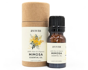 May include: A brown glass bottle with a black cap containing 100% pure and organic mimosa essential oil. The bottle is labeled with the brand name "avivni" and the text "100% Pure & Organic Mimosa Essential Oil 0.33 FL OZ (10ML)". The bottle is sitting on a brown cardboard tube with the same label.