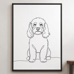 Op de afbeelding: Een ingelijste wandkunstprint met een doorlopende zwarte lijntekening van een hond met krullend haar op een witte achtergrond. De hond is zittend afgebeeld, kijkt naar voren en heeft grote ogen, hangende oren en een getextureerde vacht.