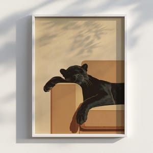 May include: A framed art print featuring a black panther resting on a brown chair. The panther is depicted in a relaxed pose, with its head resting on the armrest. The background is a light beige color with shadows.