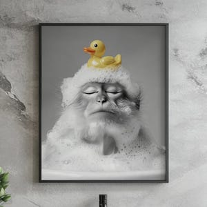 May include: A black and white photo of a monkey with a yellow rubber ducky on its head. The monkey is covered in white bubbles and has its eyes closed. The monkey appears to be relaxing in a bath.