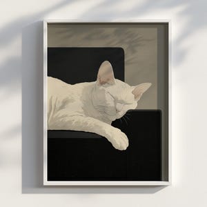 Könnte beinhalten: Ein gerahmter Kunstdruck mit einer schlafenden weißen Katze. Die Katze liegt auf einer schwarzen Oberfläche, die Augen geschlossen. Der Hintergrund ist in einem neutralen Beige gehalten, und der Druck ist in einem weißen Rahmen eingefasst.