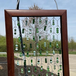 Green beaded chicken wire sun catcher in wood frame.