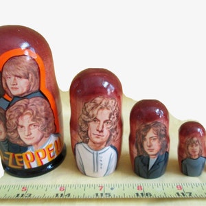 May include: Set of six nesting dolls, each painted with a different member of the rock band Led Zeppelin. The largest doll is painted with all four members of the band, and the smallest doll is painted with the band's name "Led Zeppelin".