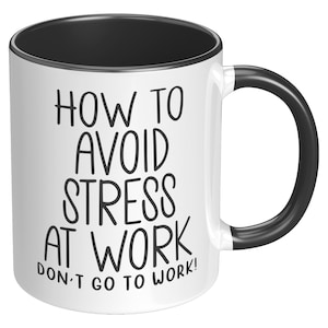 Puede incluir: Taza de cerámica blanca con interior, asa y borde negros. La taza presenta el texto "HOW TO AVOID STRESS AT WORK DON'T GO TO WORK!" en negro, en negrita, fuente sans-serif.