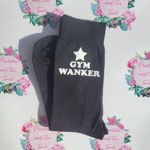 May include: A pair of black socks with a white star and the text "GYM WANKER" printed on them.