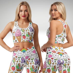 May include: White sports bra and leggings set with a colorful cartoon pattern. The pattern includes ice cream cones, strawberries, rainbows, butterflies, and hearts. The sports bra has a scoop neck and racerback design.