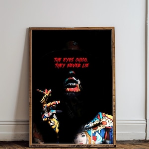 May include: A framed art print with a dark background, featuring a person with vibrant pop art style makeup and clothing. The red text reads "THE EYES CHICO. THEY NEVER LIE". The artwork is presented in a wooden frame.