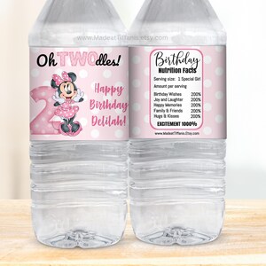K&ouml;nnte beinhalten: Zwei rosa und wei&szlig;e Wasserflaschenetiketten mit einem Cartoon-Bild von Minnie Mouse. Das Etikett auf der linken Seite lautet "Oh TWOdles!" und "Happy Birthday Delilah!" Das Etikett auf der rechten Seite lautet "Geburtstags-N&auml;hrwertangaben" und listet verschiedene Geburtstagsw&uuml;nsche und Aufregung mit 1000% auf.