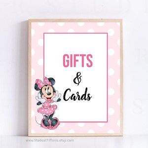 May include: Pink and white polka dot sign with a cartoon image of Minnie Mouse. The sign says "Gifts & Cards".