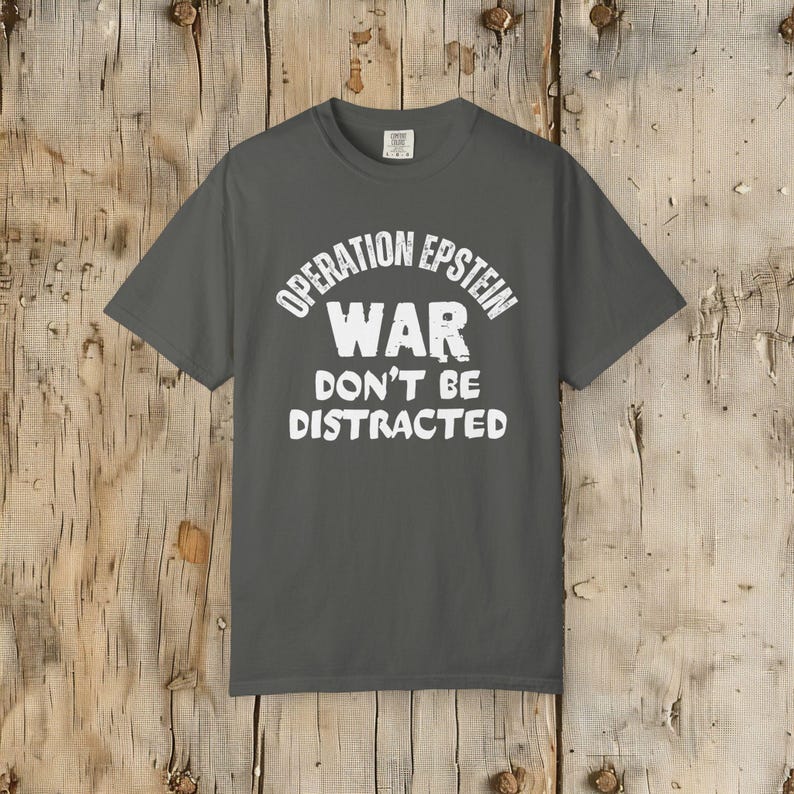Anti War with Iran Operation Epstein Don't be Distracted. This garment speaks with conviction. A heavyweight, garment-dyed tee printed with a bold, protest-forward message that draws attention without shouting. The soft, broken-in hand of garment dyeing and the relaxed fit make it comfortable for long days at rallies, vigils, or standing on the street holding a sign. Worn by someone who wants their stance to be seen and felt, it layers easily under a jacket or stands alone as a statement piece.