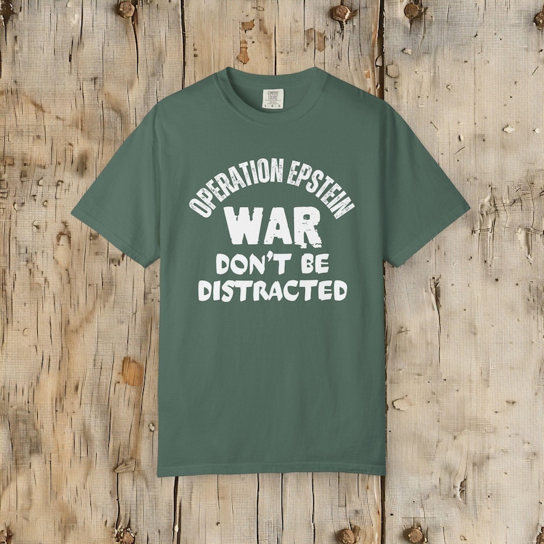 Anti War with Iran Operation Epstein Don't be Distracted. This garment speaks with conviction. A heavyweight, garment-dyed tee printed with a bold, protest-forward message that draws attention without shouting. The soft, broken-in hand of garment dyeing and the relaxed fit make it comfortable for long days at rallies, vigils, or standing on the street holding a sign. Worn by someone who wants their stance to be seen and felt, it layers easily under a jacket or stands alone as a statement piece.